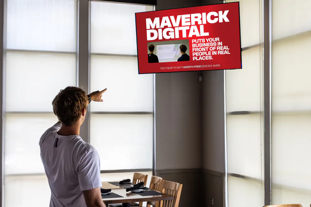 Viewer pointing at a Maverick Digital ad playing on a wall-mounted screen