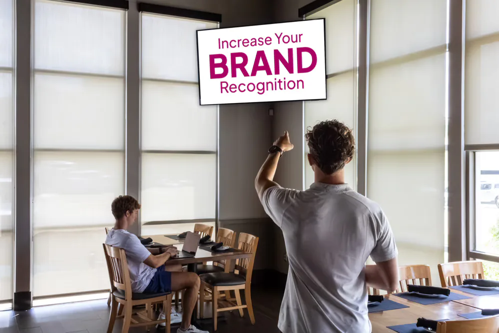 Man pointing at an "Increase Your Brand Recognition" message in a partner café