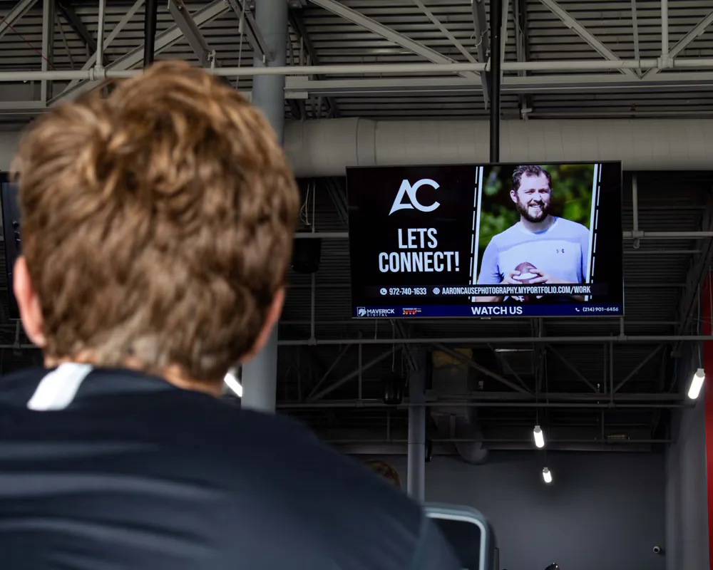 Viewer watching a client video ad on a wall-mounted screen in a gym